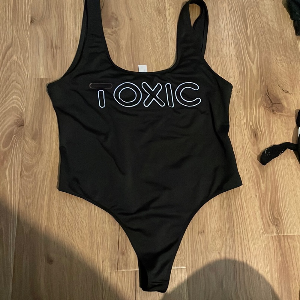 Black bodysuit says toxic in the front